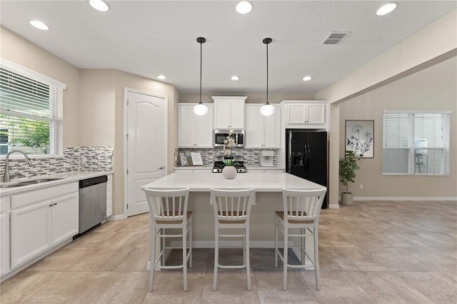 15019 Valverse Aly, Winter Garden, FL 34787 - kitchen featuring stainless steel appliances, tasteful backsplash, a center island, white cabinetry, and light countertops