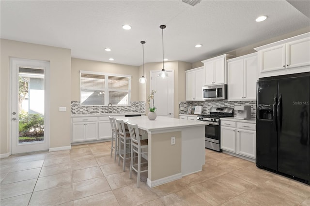 15019 Valverse Aly, Winter Garden, FL 34787 - kitchen with appliances with stainless steel finishes, decorative backsplash, a kitchen island, light countertops, and healthy amount of natural light