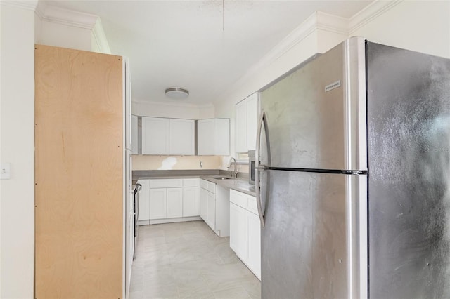 323 Scotland Dr, Daytona Beach, FL 32117 - kitchen featuring freestanding refrigerator, ornamental molding, and white cabinetry