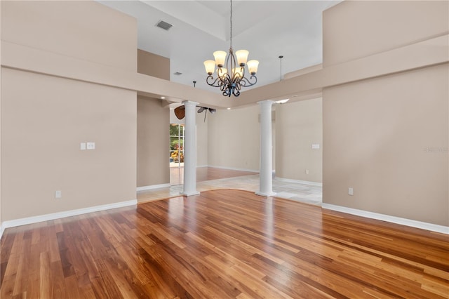 875 Bentley Green Cir, Winter Springs, FL 32708 - empty room with ornate columns, light wood finished floors, a chandelier, and a towering ceiling