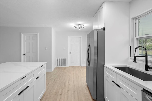 105 E Magnolia St, Davenport, FL 33837 - kitchen with appliances with stainless steel finishes, white cabinets, light wood-type flooring, and light stone countertops