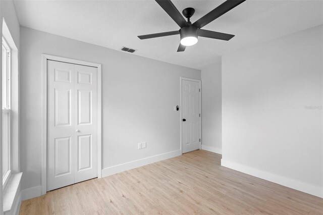 105 E Magnolia St, Davenport, FL 33837 - unfurnished bedroom with light wood-type flooring, multiple windows, ceiling fan, and a closet