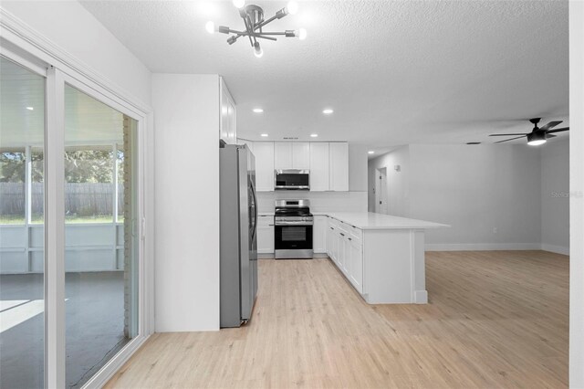 105 E Magnolia St, Davenport, FL 33837 - kitchen with appliances with stainless steel finishes, light wood-style flooring, a chandelier, a peninsula, and white cabinetry