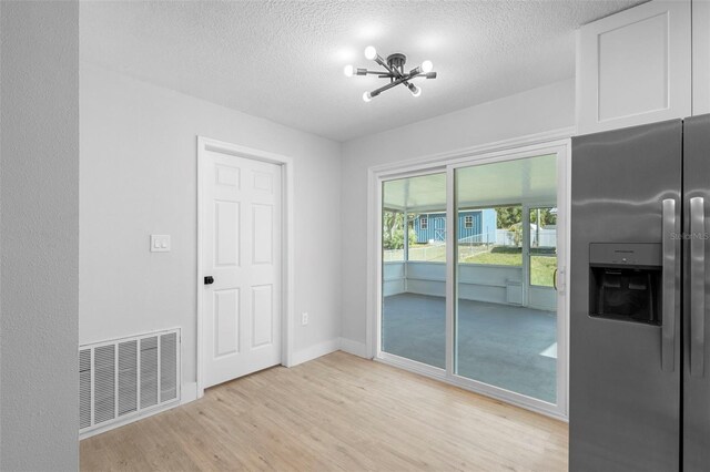 105 E Magnolia St, Davenport, FL 33837 - unfurnished room featuring a chandelier, light wood-style floors, and a textured ceiling
