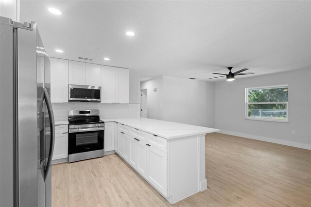 105 E Magnolia St, Davenport, FL 33837 - kitchen with stainless steel appliances, a ceiling fan, a peninsula, light wood-style flooring, and white cabinetry