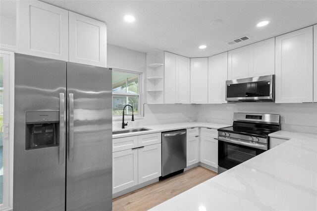 105 E Magnolia St, Davenport, FL 33837 - kitchen with appliances with stainless steel finishes, open shelves, light wood-style flooring, white cabinets, and recessed lighting