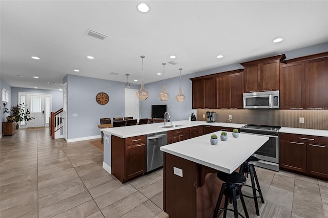 8968 Hildreth Ave, Orlando, FL 32832 - kitchen featuring appliances with stainless steel finishes, a peninsula, light countertops, a kitchen island, and backsplash