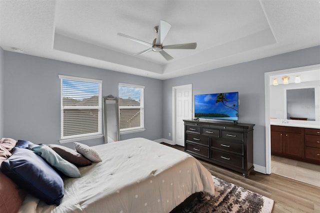 8968 Hildreth Ave, Orlando, FL 32832 - bedroom featuring a raised ceiling, wood finished floors, ensuite bathroom, and ceiling fan