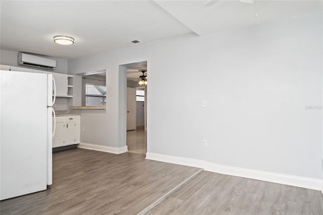 1105 Arrowsmith Ave, Orlando, FL 32809 - kitchen featuring freestanding refrigerator, a ceiling fan, a wall unit AC, and wood finished floors