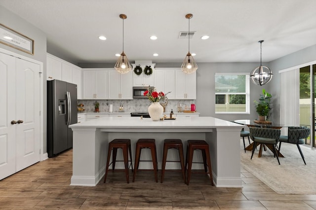 31924 Geoff, Sorrento, FL 32776 - kitchen with appliances with stainless steel finishes, wood finished floors, white cabinetry, light countertops, and tasteful backsplash