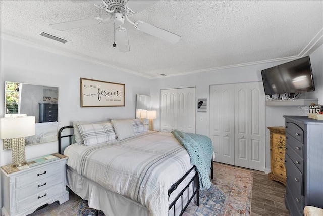2356 Date Palm Dr, Edgewater, FL 32141 - bedroom featuring two closets, a textured ceiling, dark wood-style flooring, ornamental molding, and ceiling fan