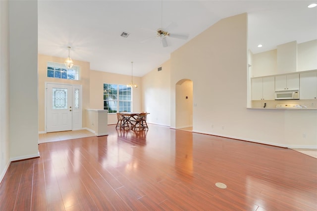 20542 Queen Alexandra Dr, Leesburg, FL 34748 - entryway featuring arched walkways, high vaulted ceiling, ceiling fan, wood finished floors, and a chandelier