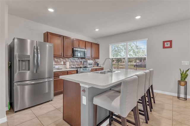 1866 Red Canyon Dr, Kissimmee, FL 34744 - kitchen with appliances with stainless steel finishes, light countertops, light tile patterned flooring, a kitchen bar, and a kitchen island with sink