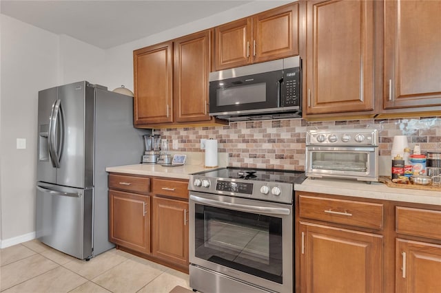 1866 Red Canyon Dr, Kissimmee, FL 34744 - kitchen featuring stainless steel appliances, light tile patterned floors, brown cabinets, and light countertops