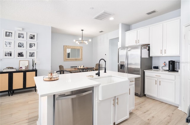 8164 Wood Sage Dr, Winter Garden, FL 34787 - kitchen featuring appliances with stainless steel finishes, light wood finished floors, a chandelier, white cabinets, and a center island with sink