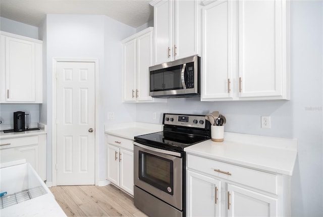 8164 Wood Sage Dr, Winter Garden, FL 34787 - kitchen with appliances with stainless steel finishes, light wood-style floors, white cabinetry, and light countertops