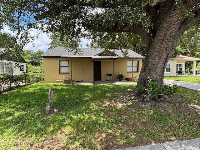 4035 Nimons St, Orlando, FL 32811 - view of front facade with a front yard, concrete block siding, and a shingled roof