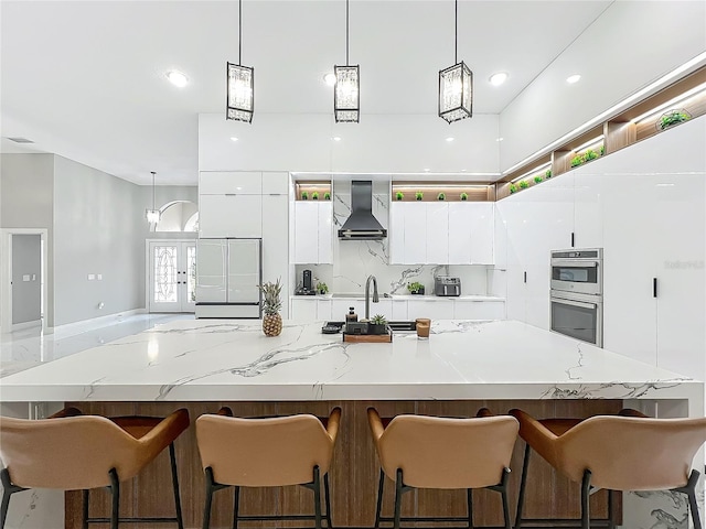 704 Forest View Ct, Winter Springs, FL 32708 - kitchen featuring double oven, wall chimney exhaust hood, modern cabinets, white cabinetry, and pendant lighting