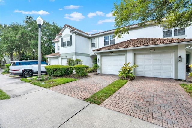 6931 Sperone St, Orlando, FL 32819 - townhome / multi-family property featuring decorative driveway, stucco siding, a garage, and a tiled roof