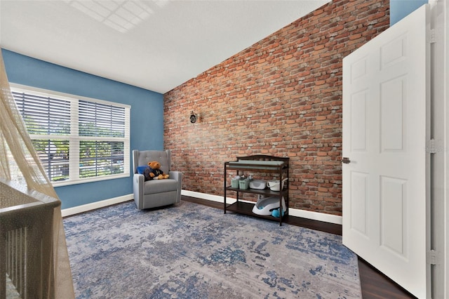 6931 Sperone St, Orlando, FL 32819 - living area featuring brick wall, vaulted ceiling, and wood finished floors