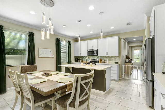 2491 Wadeview Loop, Saint Cloud, FL 34769 - kitchen featuring appliances with stainless steel finishes, healthy amount of natural light, light countertops, crown molding, and backsplash
