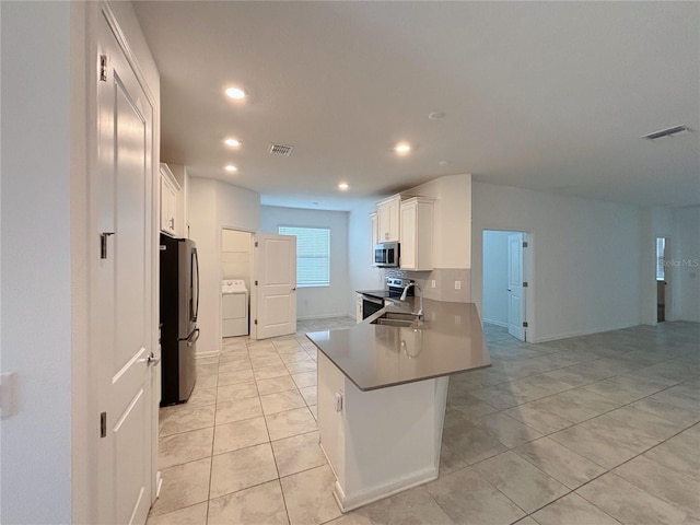6300 Chirpine Ln, Saint Cloud, FL 34771 - kitchen with washer / dryer, appliances with stainless steel finishes, recessed lighting, white cabinets, and light tile patterned floors