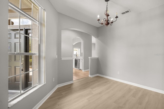 13658 Hidden Forest Cir, Orlando, FL 32828 - unfurnished room featuring arched walkways, wood finished floors, and a chandelier