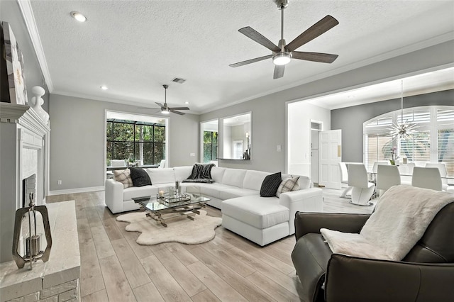 1769 Turnberry Ter, Orlando, FL 32804 - living room featuring a ceiling fan, a textured ceiling, light wood-style flooring, a fireplace with raised hearth, and crown molding