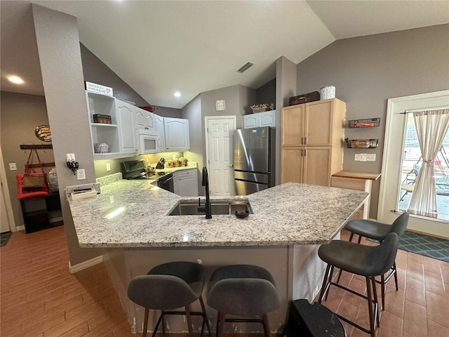 1140 Odoniel Loop S, Lakeland, FL 33809 - kitchen with freestanding refrigerator, electric range oven, vaulted ceiling, white microwave, and a peninsula