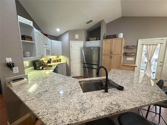 1140 Odoniel Loop S, Lakeland, FL 33809 - kitchen with freestanding refrigerator, range with electric stovetop, white microwave, vaulted ceiling, and open shelves