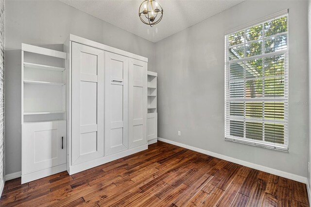 28707 Raleigh Pl, Wesley Chapel, FL 33545 - unfurnished bedroom featuring a chandelier, dark wood finished floors, and a closet