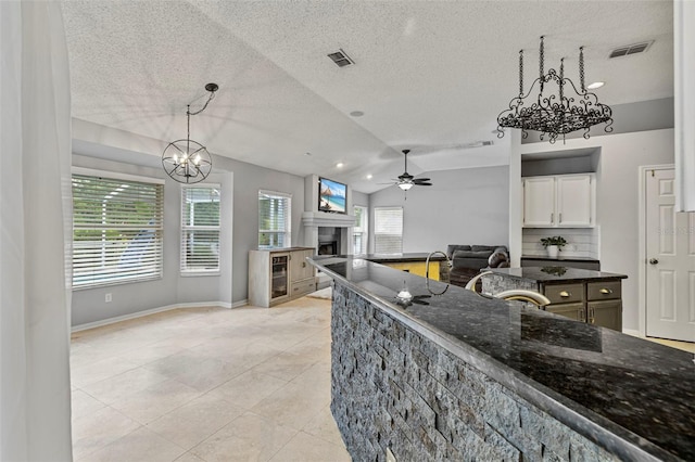 28707 Raleigh Pl, Wesley Chapel, FL 33545 - kitchen with a chandelier, a ceiling fan, dark stone counters, healthy amount of natural light, and a textured ceiling