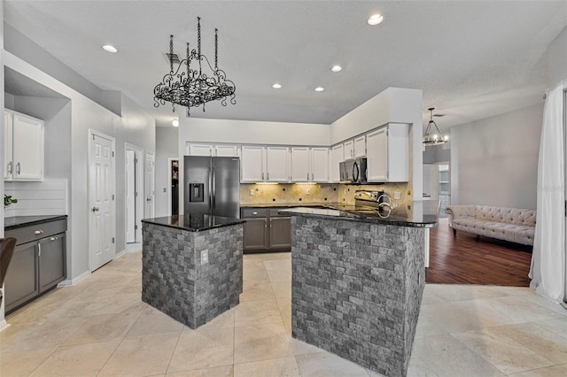 28707 Raleigh Pl, Wesley Chapel, FL 33545 - kitchen with appliances with stainless steel finishes, a chandelier, decorative backsplash, dark stone countertops, and recessed lighting