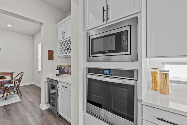 3179 Sailing Pier Ave, Winter Garden, FL 34787 - kitchen featuring stainless steel appliances, beverage cooler, light countertops, dark wood-style floors, and white cabinets