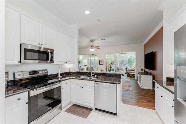 2173 Caledonian St, Clermont, FL 34711 - kitchen with stainless steel appliances, a peninsula, ornamental molding, ceiling fan, and white cabinetry