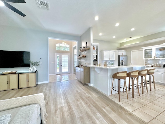 5205 Hammock Cir, Saint Cloud, FL 34771 - kitchen with stainless steel fridge with ice dispenser, white cabinetry, a breakfast bar area, light wood-type flooring, and recessed lighting