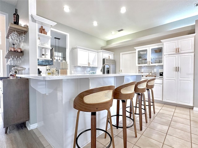 5205 Hammock Cir, Saint Cloud, FL 34771 - kitchen featuring stainless steel fridge with ice dispenser, a kitchen breakfast bar, light countertops, a peninsula, and tasteful backsplash