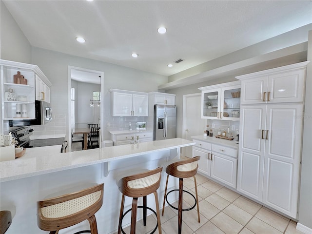 5205 Hammock Cir, Saint Cloud, FL 34771 - kitchen featuring appliances with stainless steel finishes, tasteful backsplash, open shelves, a peninsula, and a kitchen breakfast bar