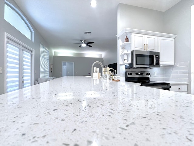 5205 Hammock Cir, Saint Cloud, FL 34771 - kitchen featuring appliances with stainless steel finishes, open shelves, light stone counters, white cabinets, and backsplash