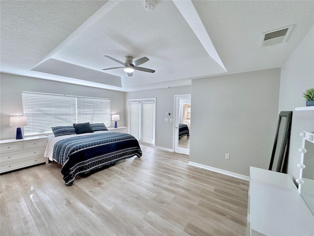 5205 Hammock Cir, Saint Cloud, FL 34771 - bedroom featuring a tray ceiling, a textured ceiling, light wood-type flooring, a ceiling fan, and a closet