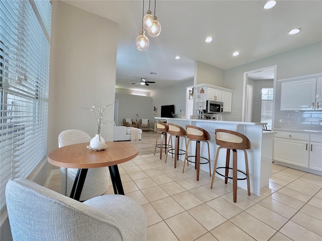 5205 Hammock Cir, Saint Cloud, FL 34771 - kitchen with stainless steel microwave, tasteful backsplash, light tile patterned floors, a breakfast bar area, and recessed lighting