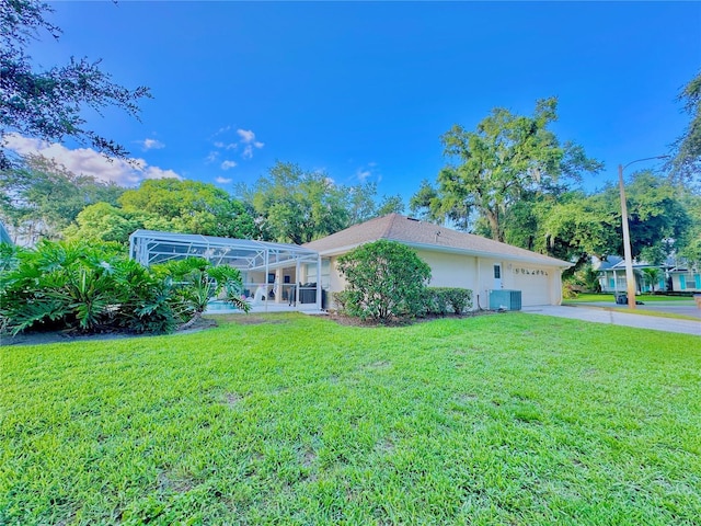 5205 Hammock Cir, Saint Cloud, FL 34771 - rear view of property with a garage, a yard, concrete driveway, glass enclosure, and stucco siding