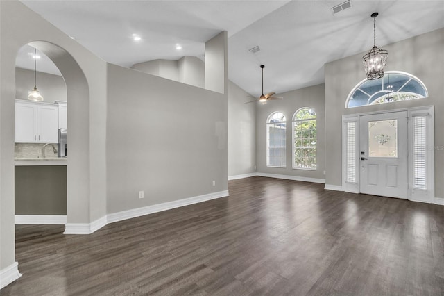 1031 Seneca Trl, Saint Cloud, FL 34772 - foyer featuring high vaulted ceiling, dark wood finished floors, arched walkways, ceiling fan, and a chandelier