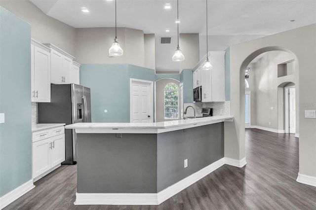 1031 Seneca Trl, Saint Cloud, FL 34772 - kitchen featuring stainless steel appliances, white cabinets, arched walkways, tasteful backsplash, and a towering ceiling