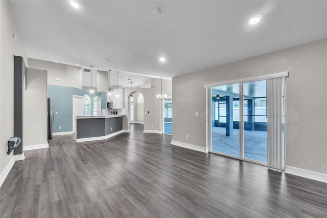 1031 Seneca Trl, Saint Cloud, FL 34772 - unfurnished living room featuring dark wood-style floors, a chandelier, arched walkways, and recessed lighting