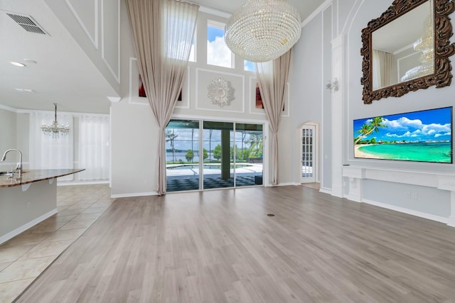 5552 Remsen Cay Ln, Windermere, FL 34786 - unfurnished living room featuring a chandelier, a towering ceiling, plenty of natural light, and wood finished floors