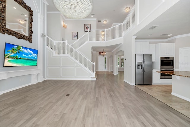 5552 Remsen Cay Ln, Windermere, FL 34786 - unfurnished living room featuring a chandelier, stairway, a towering ceiling, light wood-style floors, and ornamental molding