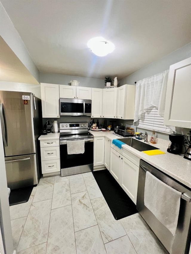 1034 Villa Ln Unit 18, Apopka, FL 32712 - kitchen with appliances with stainless steel finishes, light countertops, white cabinets, and light marble finish floors