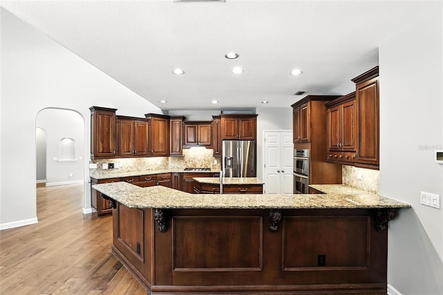 2890 Wild Ginger Ct, Winter Park, FL 32792 - kitchen featuring stainless steel appliances, decorative backsplash, light stone counters, light wood-style floors, and a peninsula