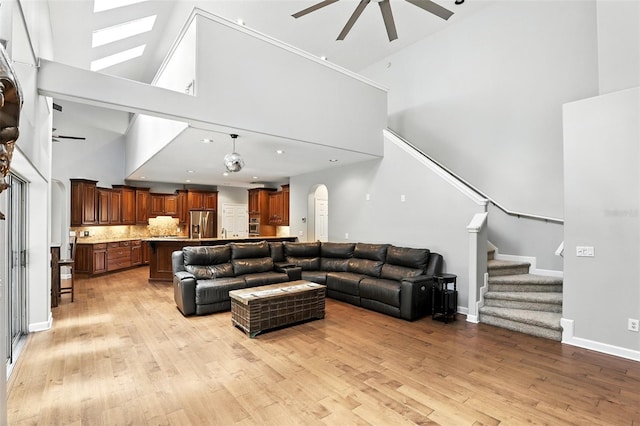 2890 Wild Ginger Ct, Winter Park, FL 32792 - living room featuring ceiling fan, a towering ceiling, light wood-style flooring, stairs, and arched walkways